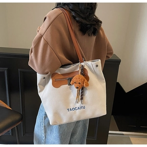 Detail view of large canvas tote bag with brown leather straps and puppy pendant