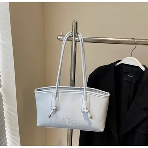 Détail du sac cabas en cuir bleu clair avec nœud décoratif et gaufrage de la marque