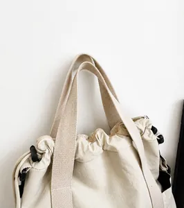 Detail of canvas tote bag showing wide woven handle and drawstring closure system