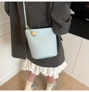 Detail of light blue bucket bag showing lychee grain leather and wooden bead charm