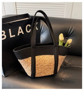 Detail of contrast woven handbag with black braided handles on a leather sofa