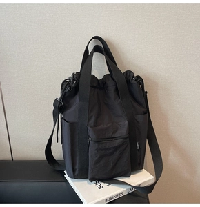 Detail of black waterproof nylon tote bag with drawstring closure and front zipper pocket