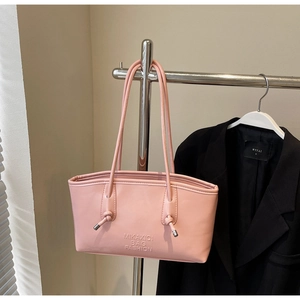 Détails d'un sac à main rose en cuir avec poignées nouées et lettrage embossé élégant