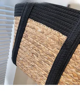 Detail of tight twill weave straw tote bag with reinforced black cotton handles