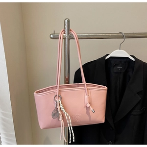 Vue détaillée du sac cabas en cuir rose avec logo embossé et breloque de tennis
