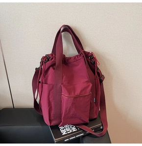Detail view of burgundy nylon tote showing waterproof texture and functional zippers
