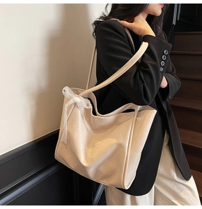 Detail of a large cream tote bag featuring a decorative lace bow on the shoulder strap