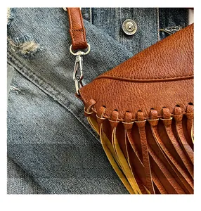 Detaillierte Makroansicht der braunen Lederquaste und des silbernen Karabinerhakens dieser Tasche