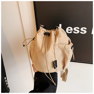 Detail of beige nylon bucket bag featuring a mesh side pocket and drawstring closure