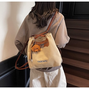 Detail of canvas tote bag with brown straps, embroidery and teddy bear charm
