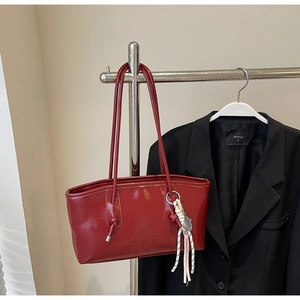 Détail du sac cabas en cuir verni rouge avec logo embossé et gland décoratif
