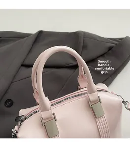 Detail of round handles on a pale pink Boston bag featuring smooth PU leather and silver hardware