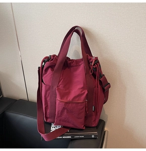 Detail of burgundy nylon tote bag featuring drawstring closure and adjustable strap