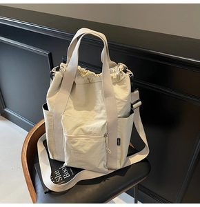 Detail view of large canvas tote bag with drawstring closure and front zipper pocket