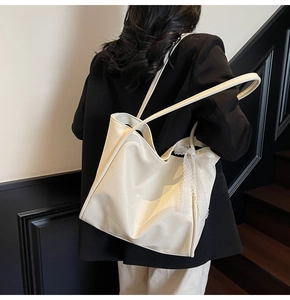 Close-up of a cream white leather tote bag featuring a delicate white lace bow detail