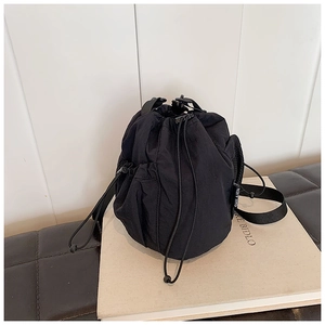 Close-up of black nylon bucket bag featuring a drawstring closure and logo fabric label