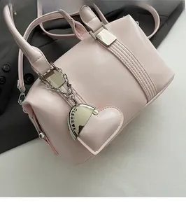 Detail of pink Boston bag showing leather texture, heart pendant, and silver metal hardware