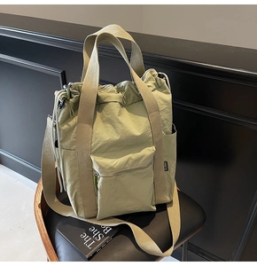 Detail of light green waterproof nylon tote bag with drawstring closure on a black chair