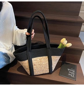 Gros plan d'un grand sac cabas en paille bicolore noir et naturel sur un escalier