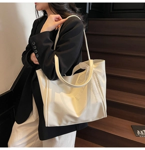 Close-up of cream tote bag with lace bow details on a model in an urban setting