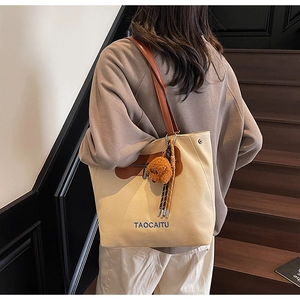 Detail of canvas tote bag with brown leather straps and cute puppy pendant on stairs