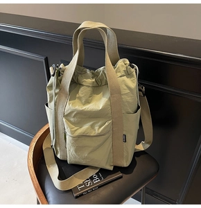 Close-up of sage green nylon tote bag with side pocket and adjustable shoulder strap