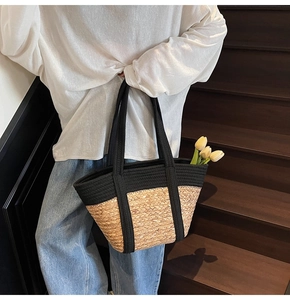 Gros plan d'un grand sac cabas en paille tressée avec bordure et anses en tissu noir