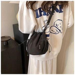 Detail view of black nylon bucket bag featuring a side mesh pocket and white brand woven label