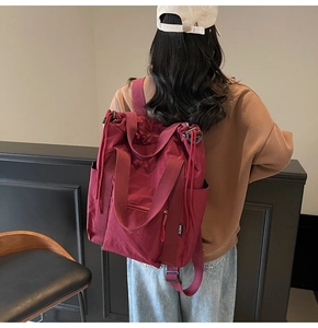 Deep red nylon backpack detail showing durable straps and side drawstring on the back view