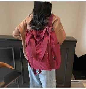 Detail of burgundy canvas tote bag with drawstring closure and multifunctional straps