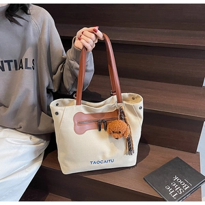 Detail of canvas tote bag featuring bone-shaped pocket and cute dog plush pendant charm