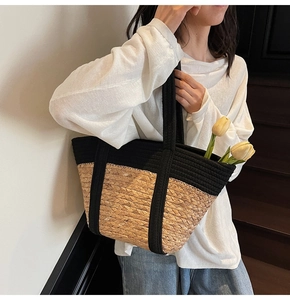 Détail du sac cabas en paille tissée et poignée en corde noire sur l'épaule d'une femme