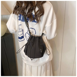 Detail of black nylon bucket bag featuring drawstring closure and side mesh pocket
