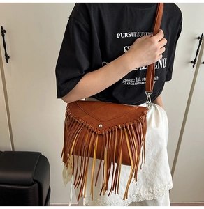 Brown leather messenger bag with long bohemian tassels worn by a model in a casual setting