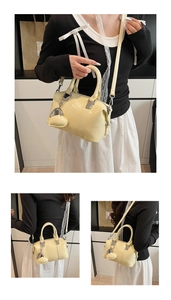 Detail of cream Boston bag with heart charm, silver zippers and top handles close-up