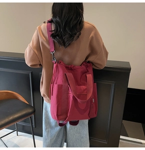 Detail of a dark red canvas multipurpose tote bag showing drawstring closure and side pocket