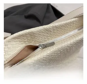 Detail of silver metal zipper and woven texture on a cream white hobo tote bag