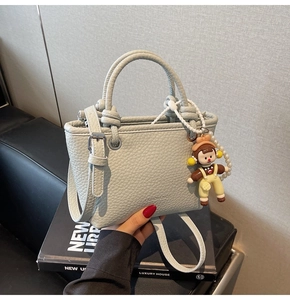 Detail of light green bucket bag featuring lychee texture and cute cartoon charm decoration