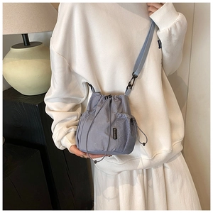Detail of grey-blue nylon bucket bag with side mesh pocket and adjustable shoulder strap