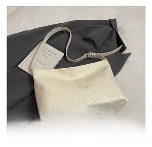 Detail of cream woven tote bag texture with adjustable leather shoulder strap
