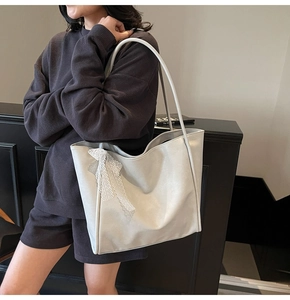 Detail view of large faux leather tote bag with elegant white lace trim and fine texture