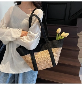 Détail d'un sac cabas bicolore en paille avec anses en corde noire et texture naturelle