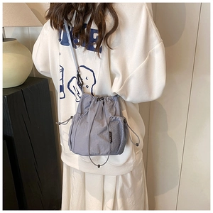 Detailed side view of nylon bucket bag featuring a mesh pocket and adjustable drawstrings