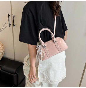 Detail der rosa Boston Bag mit glänzender Textur, Spitzenanhängern und Crossbody-Stil