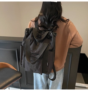 Rear view of model wearing a large black nylon functional tote bag in urban utility style
