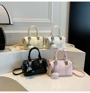 Detailed view of glossy leather Boston handbags in four colors with heart pendants