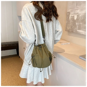 Detail of army green nylon bucket bag with adjustable shoulder strap and mesh side pocket