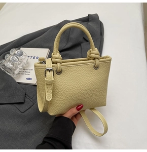 Close-up of pebble-textured leather bucket bag with knotted handles in light yellow