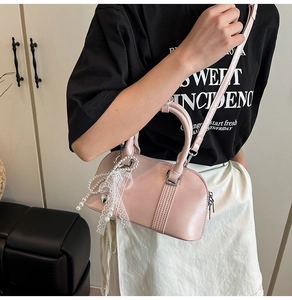Detailansicht einer blassrosa Handtasche mit Spitzenbogen und Perlenanhänger Verzierung