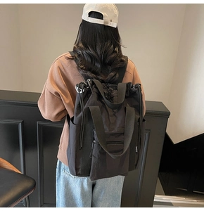Rear view of model wearing a black multifunctional nylon backpack with side pockets